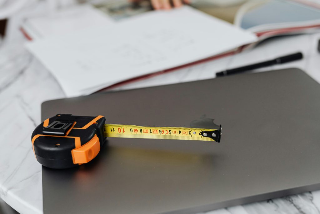 Close-up image of a measuring tape and a laptop on a work desk, representing precision in work.